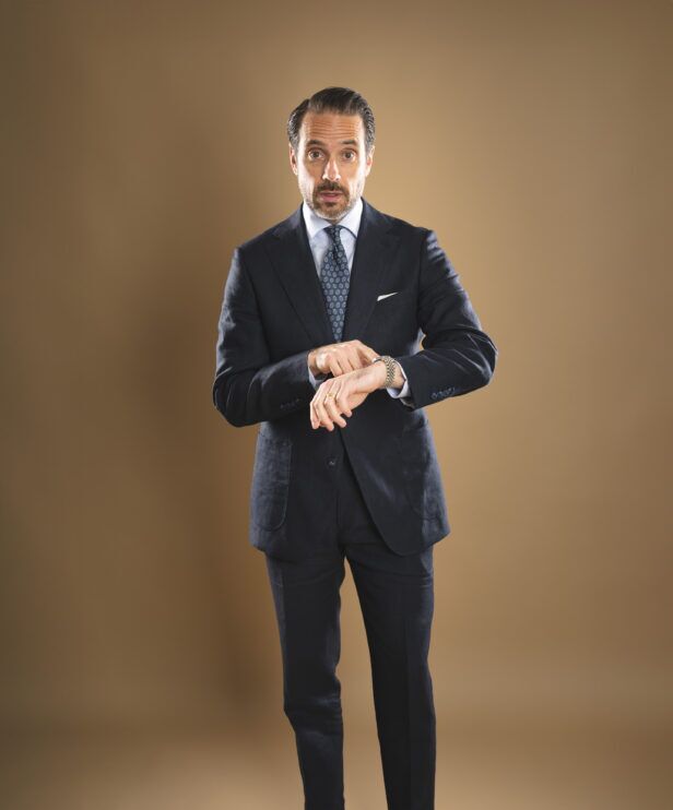 Navy linen two-button suit with light blue shirt and blue medallion silk tie, worn by a model