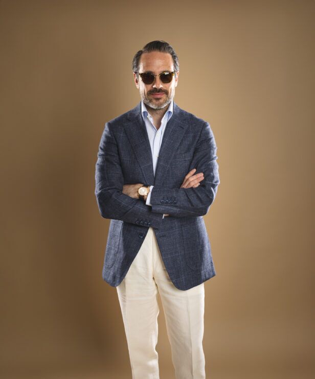 Navy checked linen sport coat with light blue shirt and cream trousers, worn by a model