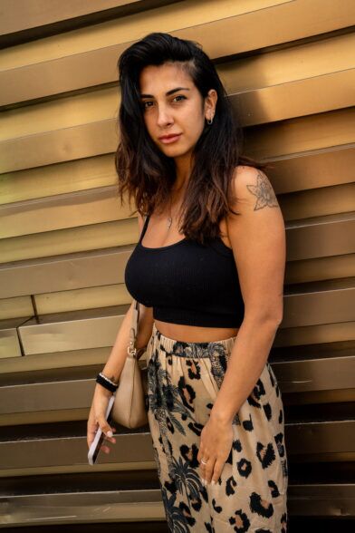 Black ribbed crop top with tan leopard and palm print trousers and beige shoulder bag, street style scene