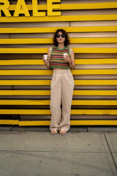 Striped crochet knit cropped tank with beige wide-leg pleated trousers and sandals, worn on a city street