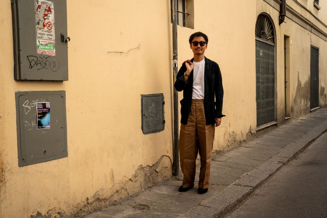 Dark green corduroy shirt jacket with white tee and tan wide-leg trousers, worn by a model on a street
