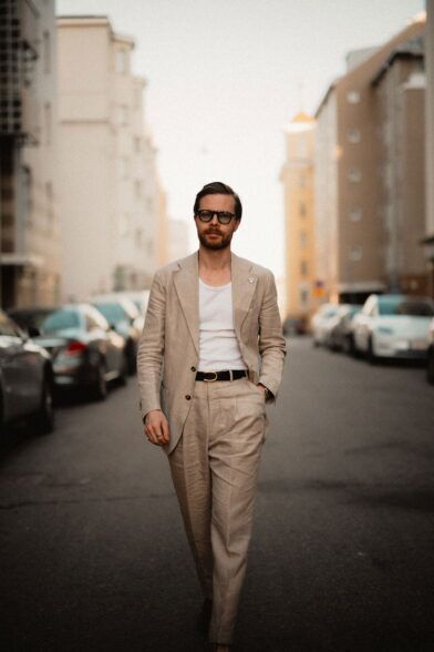 Beige linen suit with white tank top and black belt, worn by a model on a city street