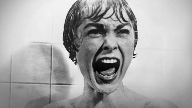 Black and white film still of a woman screaming in a tiled shower, editorial image with no product shown