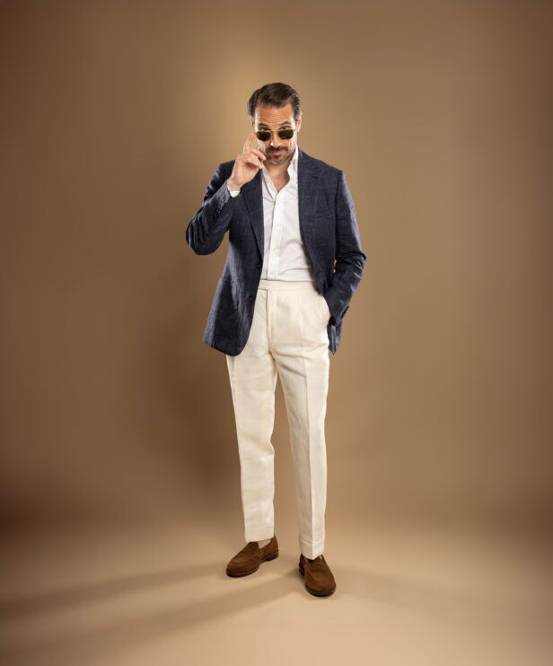 Navy plaid linen sport coat with white shirt, cream trousers and brown suede loafers, worn by a model