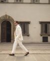 Cream linen suit with white shirt, pale tie and brown suede loafers, worn by a model on a city street