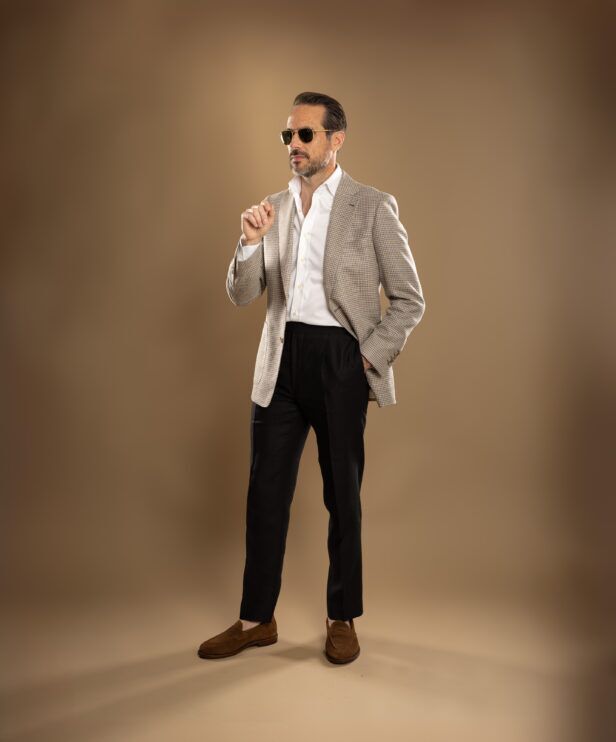 Tan and cream houndstooth sport coat with white shirt, black trousers and brown suede loafers, worn by a model
