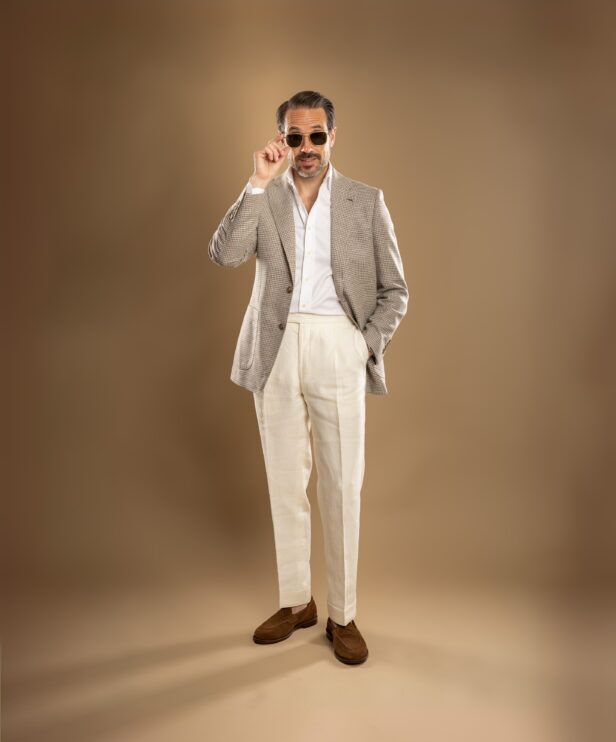 Tan houndstooth sport coat with white shirt, cream linen trousers and brown suede loafers, worn by a model