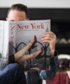 Taschen New York photography book held open by a man in a denim shirt in a living room, a lifestyle scene