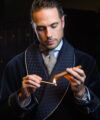 Navy quilted shawl collar smoking jacket with a houndstooth tie, lighting a cigar