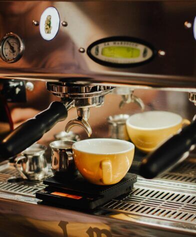 Yellow cup on a scale beneath an espresso machine portafilter, a close-up