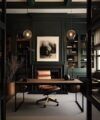 Dark green panelled home office with walnut desk, tan leather chair and glass globe pendants, an interior scene