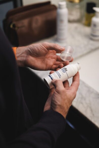 Aerosol can of SPF 40 sunscreen mist held in both hands over a sink