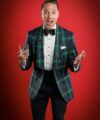 Green and navy tartan dinner jacket with a black bow tie, worn against a red backdrop