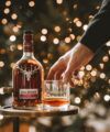 Dalmore Cigar Malt whisky bottle and a filled tumbler on a tray by a lit tree