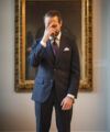 Navy chalk stripe suit with a burgundy dotted tie, worn by a model in a gallery