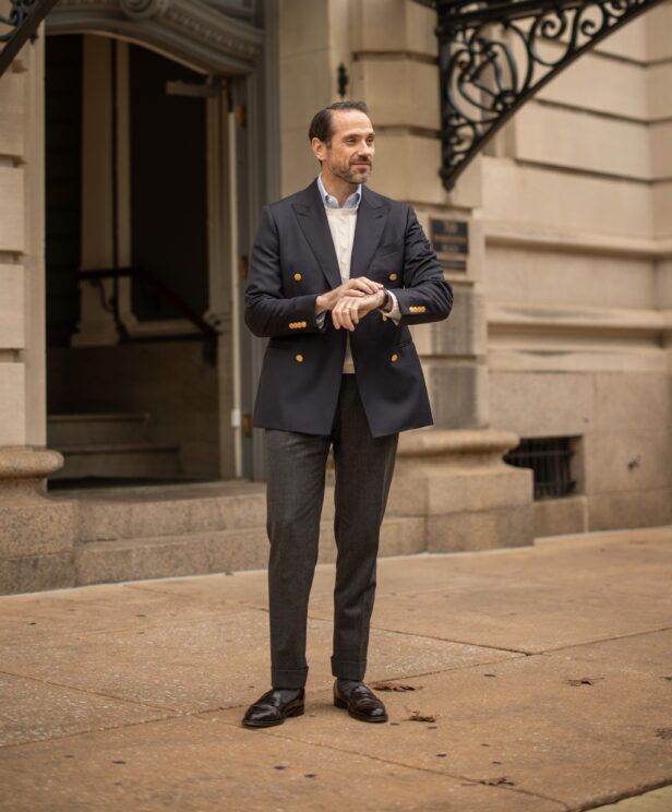 Navy double-breasted blazer with cream cable sweater and grey flannels, full length