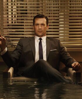 Grey suit with a white shirt and dark tie, worn by a seated man in a flooded office