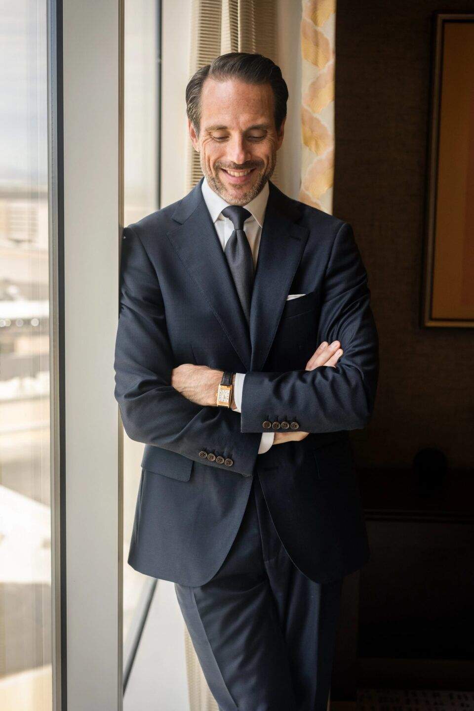Navy subtle plaid wool suit with peak lapels, white shirt, charcoal tie and white pocket square, worn by a model