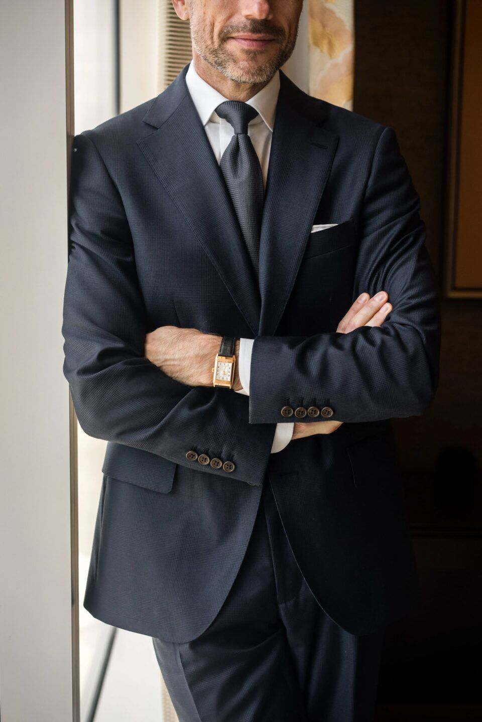 Navy subtle glen plaid wool suit with white shirt, charcoal grenadine tie and white pocket square, worn by a model