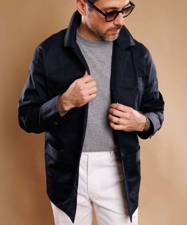 Navy cotton chore coat over a grey sweater, a close-up of the patch pockets and collar