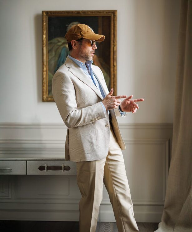Tan glen plaid blazer with blue shirt, stone trousers and a corduroy cap, worn by a model
