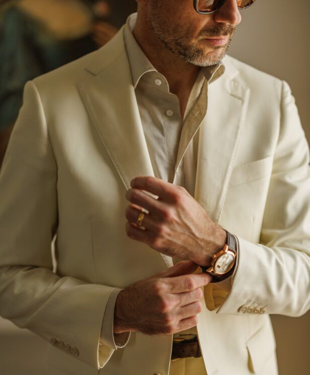 Ivory twill suit with a cream shirt and gold watch, a close-up of the cuff and lapel