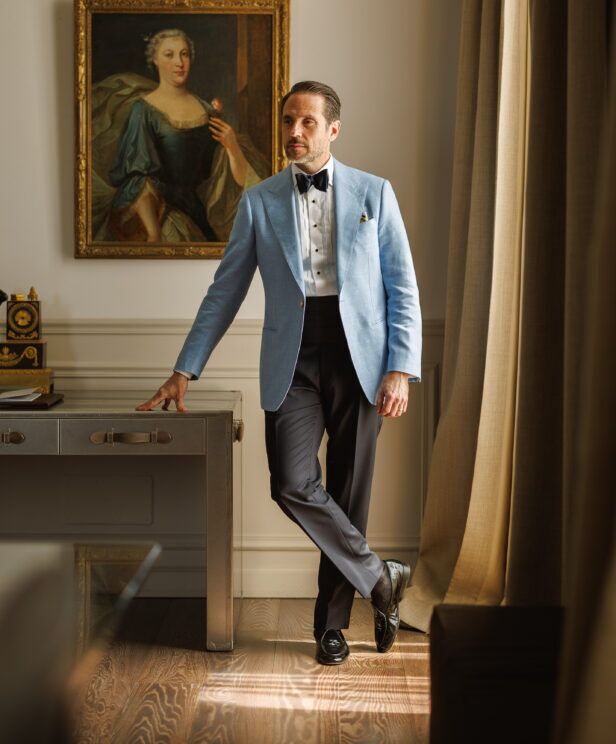 Light blue dinner jacket with navy bow tie, cummerbund and black trousers, worn by a model