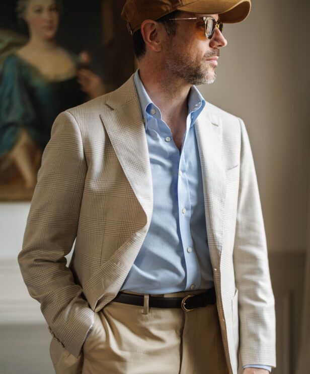 Light tan glen plaid blazer with a blue shirt and cap, a close-up of the lapel and belt