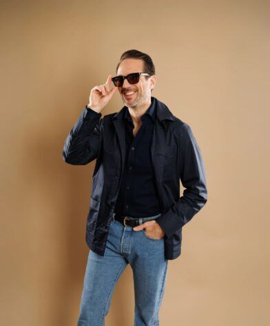Navy cotton chore coat over a navy shirt with light jeans, worn by a model