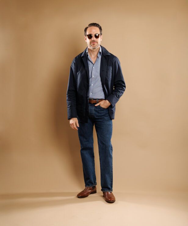 Navy cotton chore coat over a chambray shirt with dark jeans and brown boots, full length