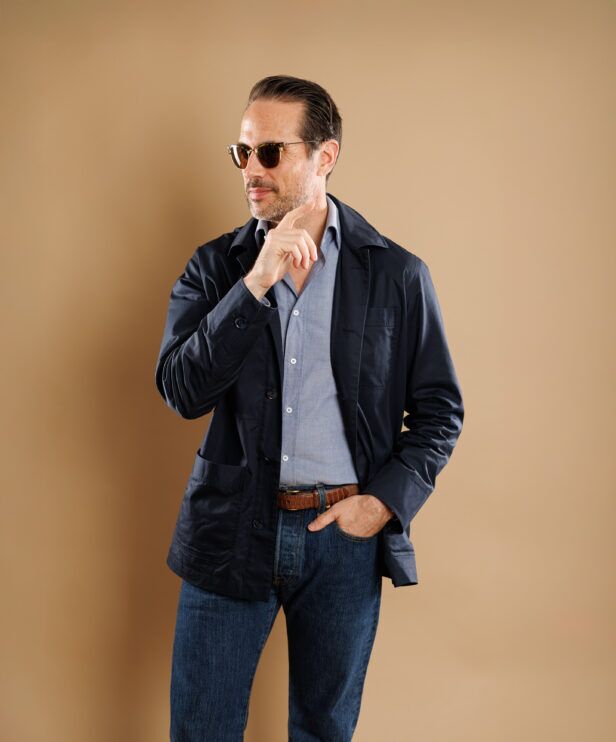 Navy cotton chore coat over a chambray shirt with dark jeans, worn by a model
