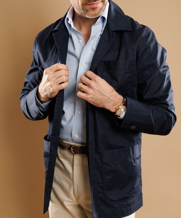 Navy cotton chore coat over a pale blue shirt, a close-up of the front and patch pockets
