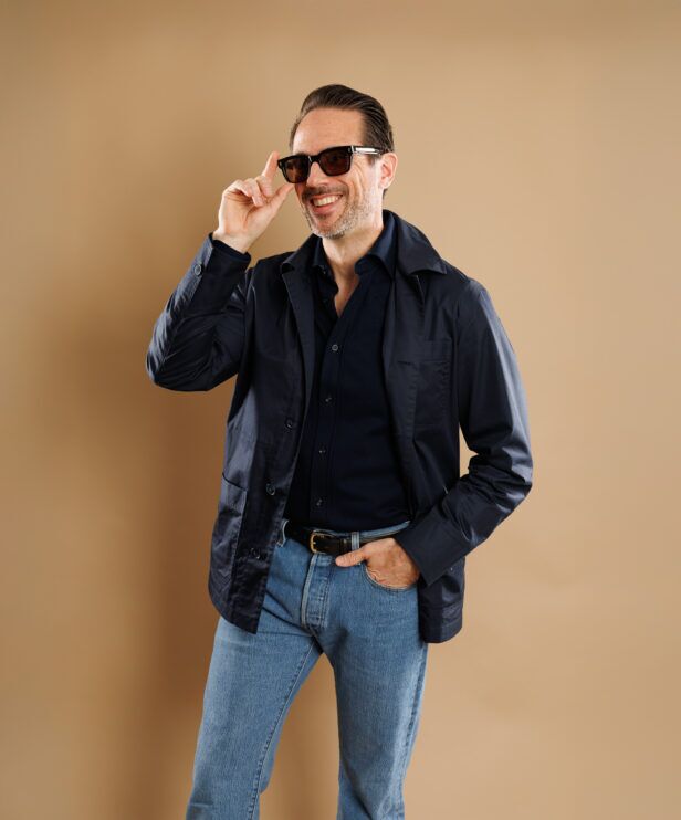 Navy cotton chore coat over a navy shirt with light jeans, worn by a model