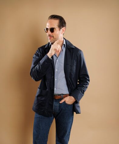 Navy cotton chore coat over a chambray shirt with dark jeans, worn by a model