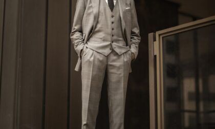 Light grey three-piece wool suit with white shirt, black knit tie and black oxfords, worn by a model