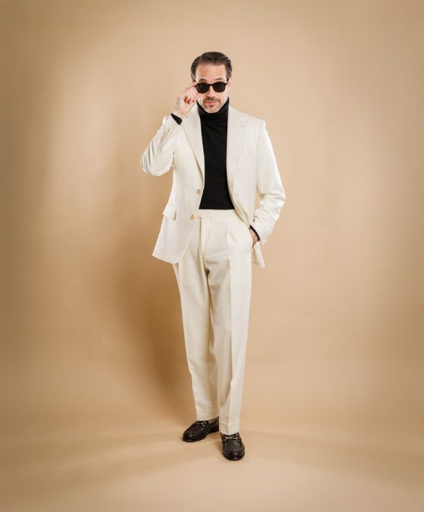 Cream flannel suit with peak lapels, worn with a black turtleneck and brown bit loafers by a model