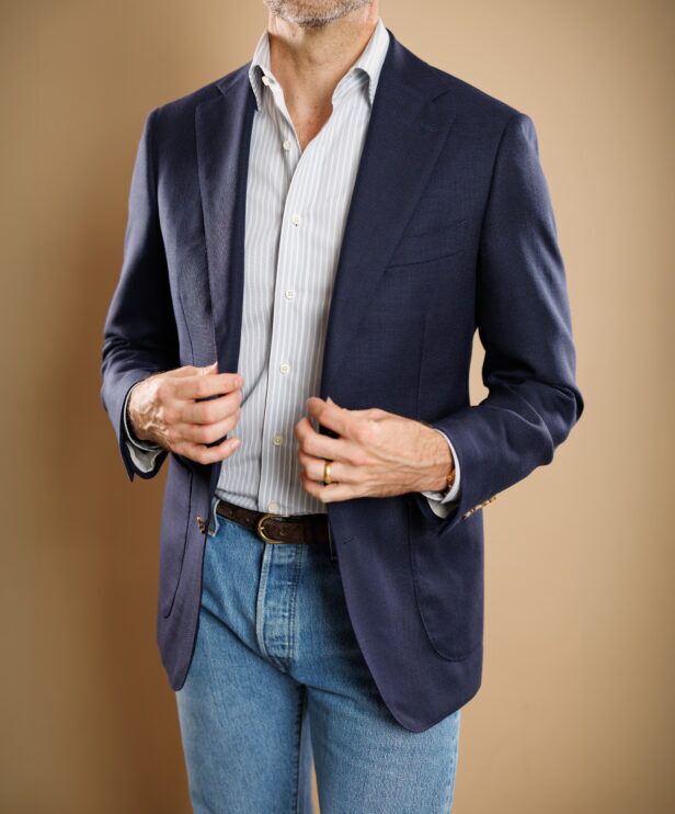 Navy hopsack sport coat with blue striped shirt, brown suede belt and light wash jeans, worn by a model