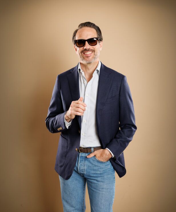 Navy hopsack sport coat with blue striped shirt, brown suede belt and light wash jeans, worn by a model
