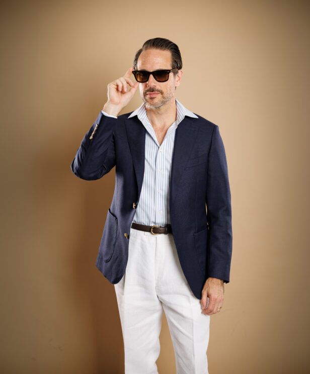 Navy hopsack sport coat with blue striped shirt and white linen trousers, worn by a model