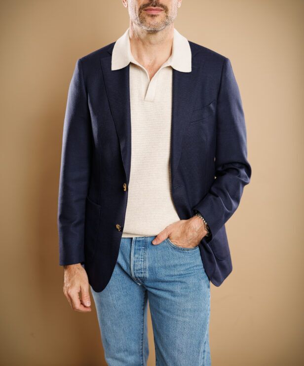 Navy hopsack sport coat with patch pockets, cream knit polo and light blue jeans, worn by a model