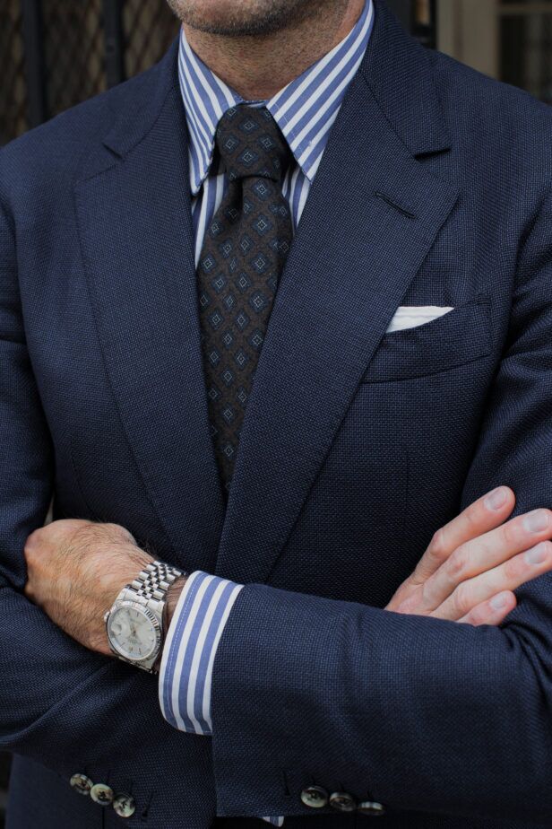 Navy hopsack blazer with blue striped shirt, brown diamond-medallion tie and white pocket square, worn by a model