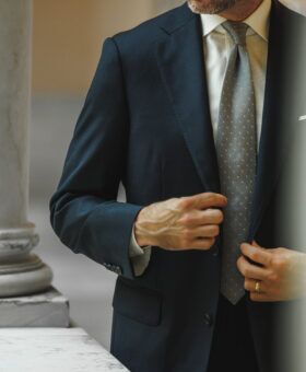 Teal blue wool suit jacket with white shirt and grey dotted silk tie, worn by a model