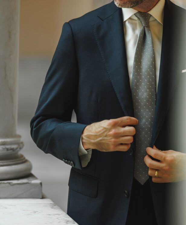 Teal blue wool suit jacket with white shirt and grey dotted silk tie, worn by a model